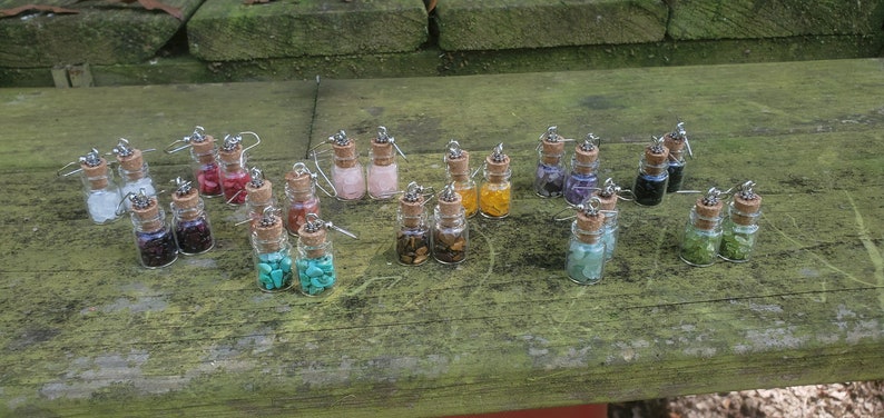 Twelve pairs of (twenty-four total) glass bottle earrings. (From top left to bottom right) clear quartz, bamboo coral, rose quartz, citrine, amethyst, onyx, red garnet, red agate, magnesite, tiger's eye, green aventurine, and peridot.